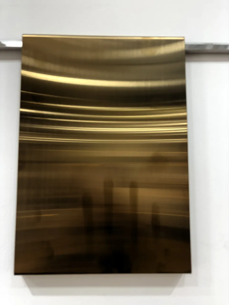 Gold PVD stainless steel sheet with a reflective brushed surface, on display